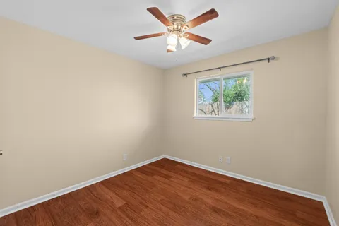an empty room with wooden floor and ceiling fan