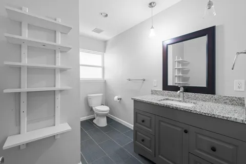 a bathroom with a granite countertop sink a toilet and a mirror