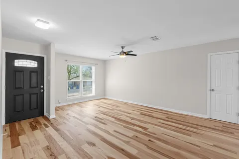 a view of an empty room with wooden floor and a window