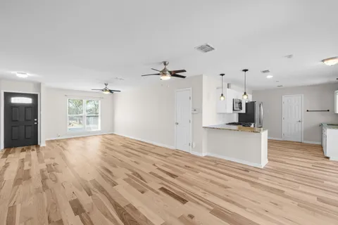 a view of a kitchen with kitchen island a sink wooden floor and a large window