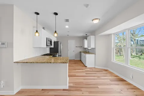 a view of a kitchen with kitchen island a sink wooden floor and a large window