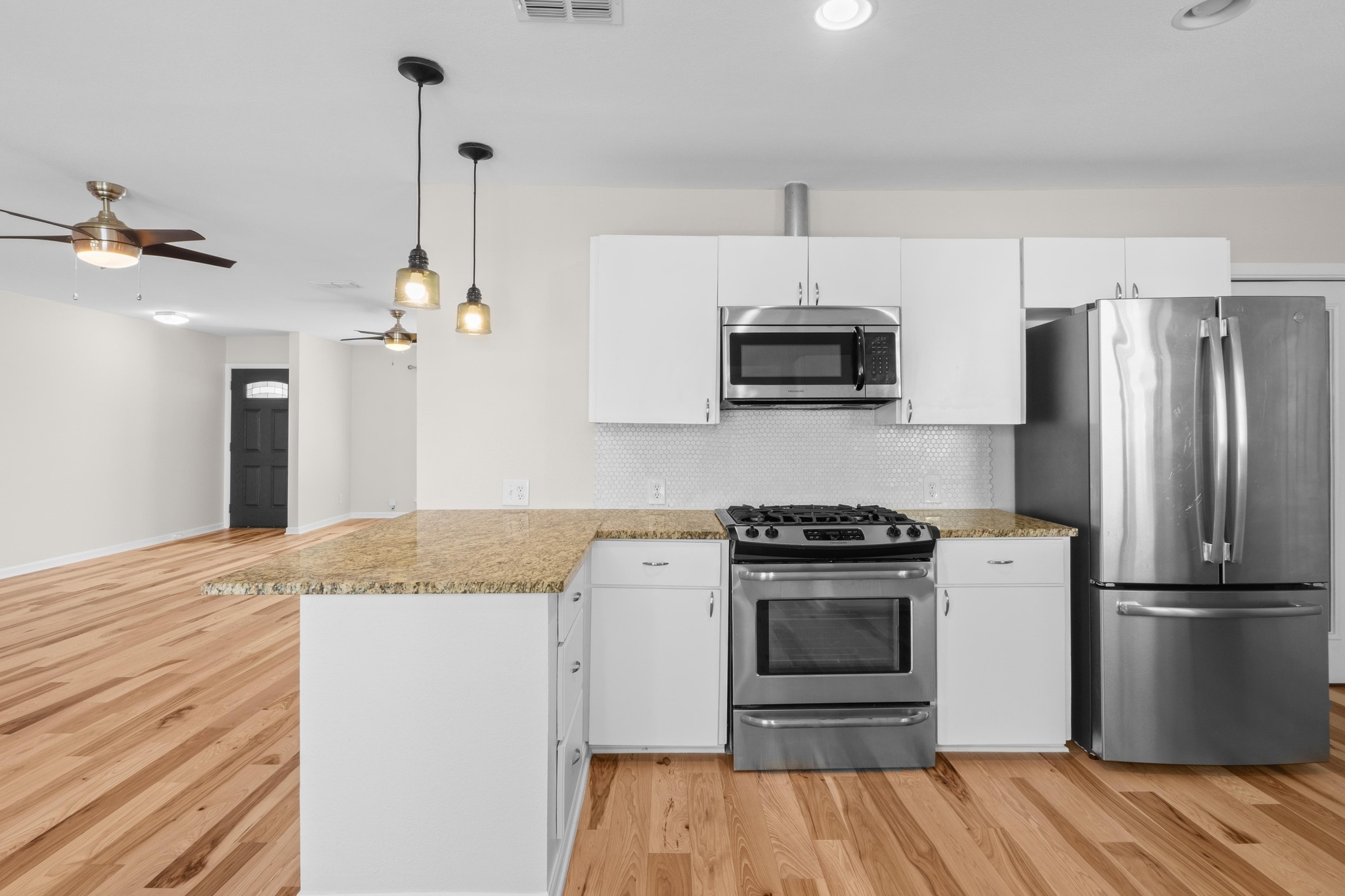 2312 Rogge Lane Austin, TX 78723 - Photo 10 of 34 Kitchen with stainless steel appliances, white cabinetry, light stone counters, and light wood finished floors.