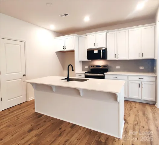 a kitchen with kitchen island white cabinets and sink