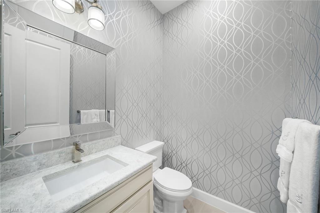 9672 Montelanico Loop, Unit 203 Naples, FL 34119 - Photo 23 of 49 a bathroom with a sink vanity mirror and toilet