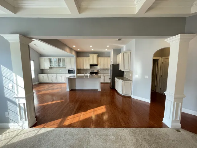 a kitchen with stainless steel appliances granite countertop a stove a sink a refrigerator white cabinets and wooden floor