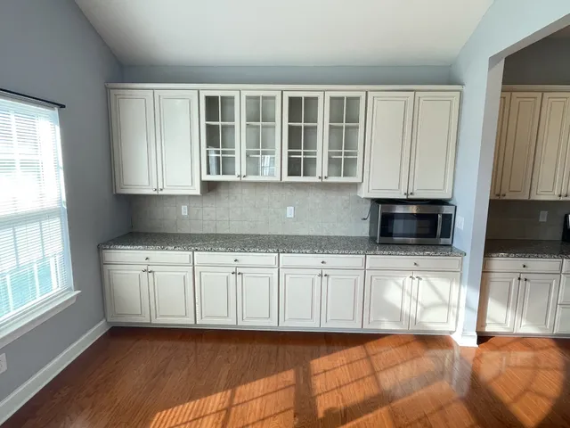 a kitchen with stainless steel appliances granite countertop a stove a sink a microwave a refrigerator and white cabinets