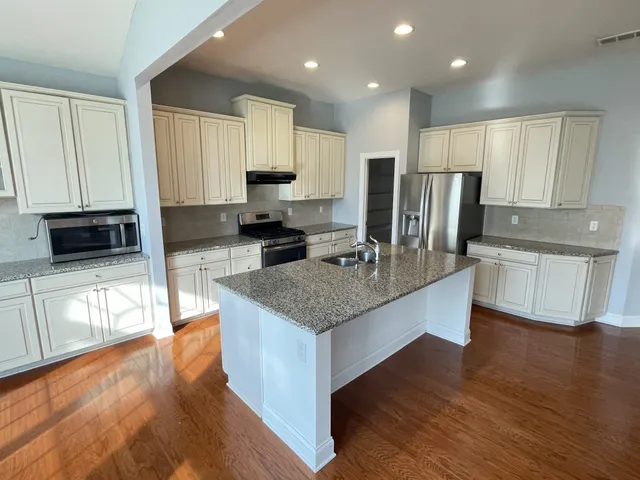 a kitchen with granite countertop white cabinets and stainless steel appliances
