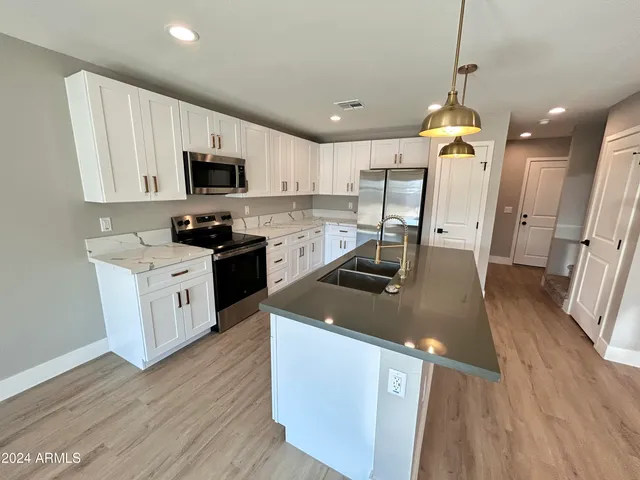 a kitchen with stainless steel appliances granite countertop a sink a stove and a wooden floors