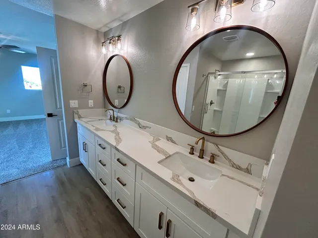 a bathroom with a granite countertop sink a toilet a mirror and shower