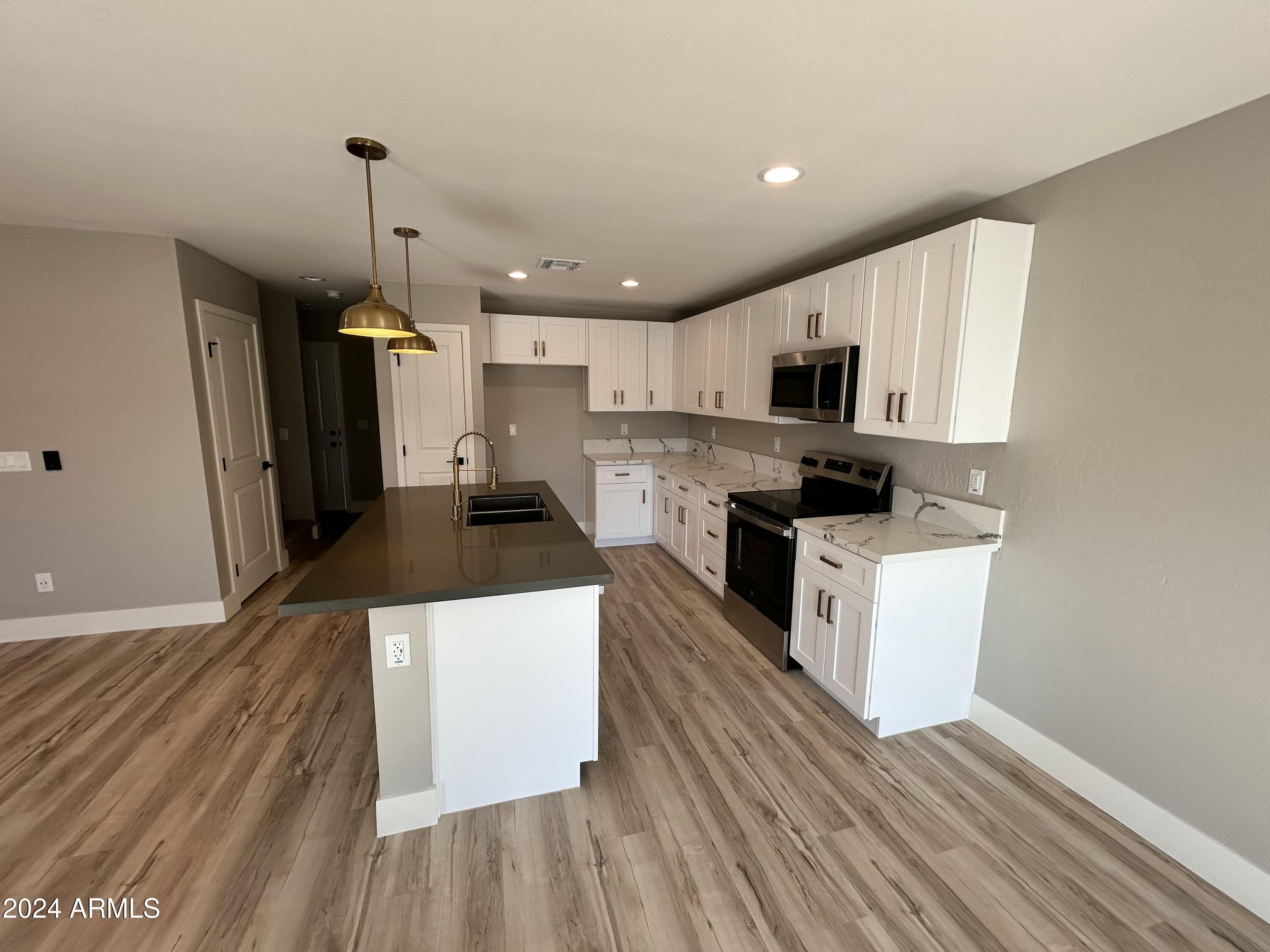 825 West Dobbins Road Phoenix, AZ 85041 - Photo 63 of 99 a kitchen with kitchen island wooden floors white cabinets and stainless steel appliances