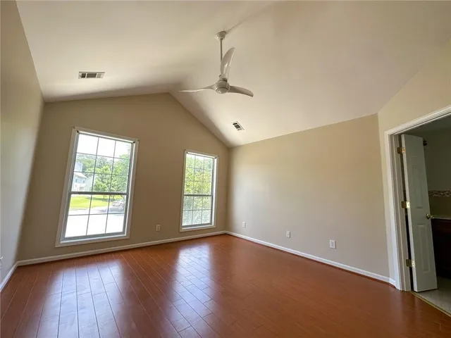 an empty room with wooden floor and windows