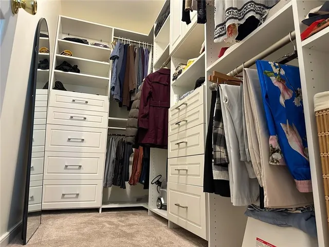a view of walk in closet with clothes and shoes