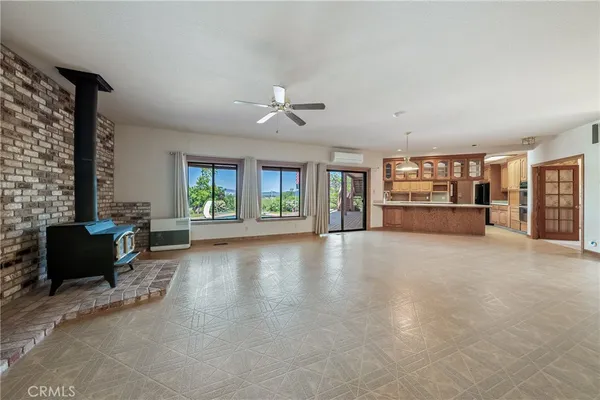 an empty room with chandelier fan and windows