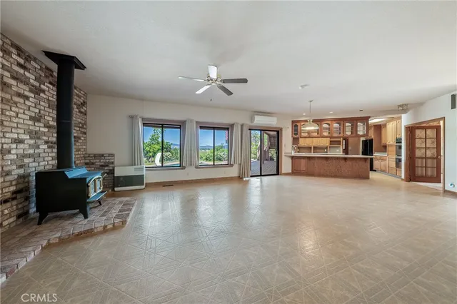 an empty room with chandelier fan and windows