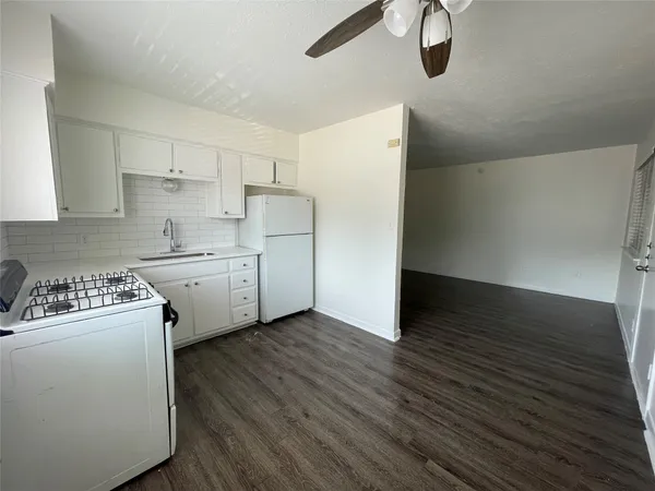a kitchen with cabinets a sink and white appliances