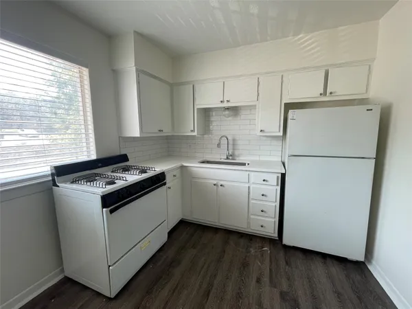 a kitchen with white cabinets appliances a sink and a window