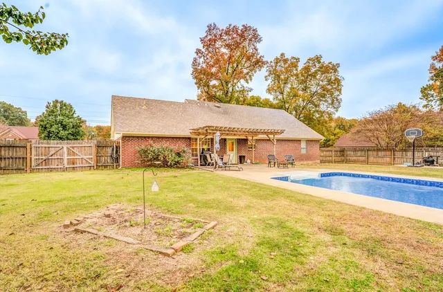 a view of house with swimming pool and yard