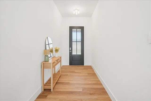 a hallway with wooden floor chandelier and entryway