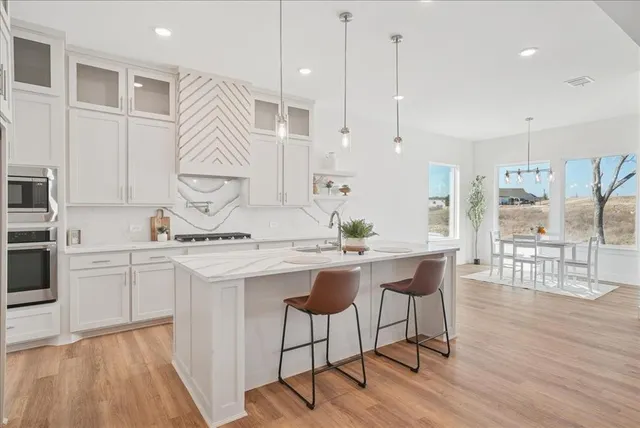 a kitchen with a sink a stove a refrigerator and white cabinets with wooden floor