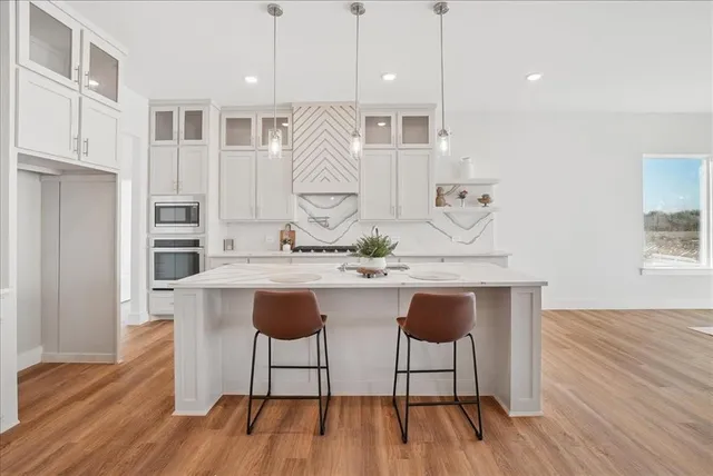 a kitchen with stainless steel appliances granite countertop a kitchen island hardwood floor sink stove and wooden cabinets