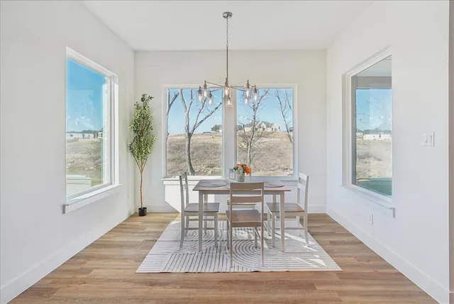 a dining room with chandelier and wooden floor