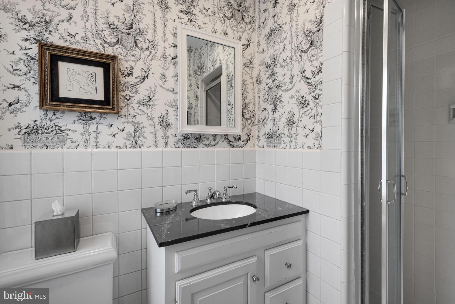 7721 Maryknoll Avenue Bethesda, MD 20817 - Photo 17 of 33 a bathroom with a granite countertop sink and a mirror