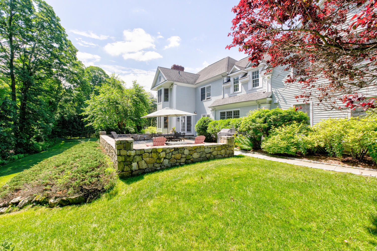 881 Valley Road New Canaan, CT 06840 - Photo 28 of 37 a front view of a house with a yard table and chairs