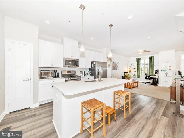 a large kitchen with kitchen island a sink a stove and a chandelier