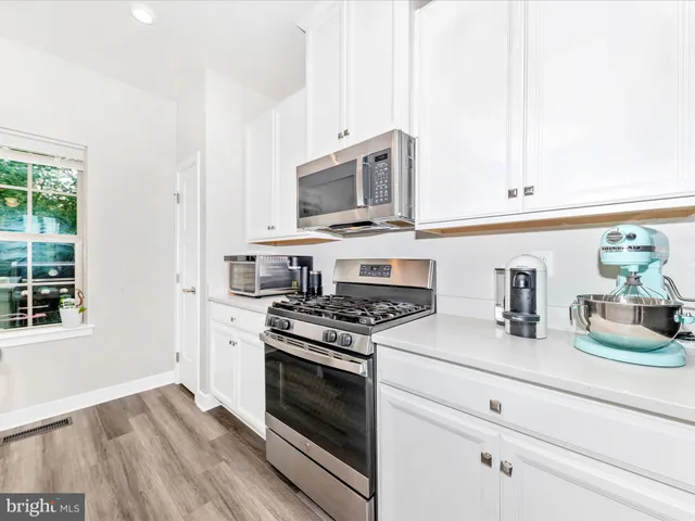 a large kitchen with kitchen island a stove a sink a center island and wooden floor