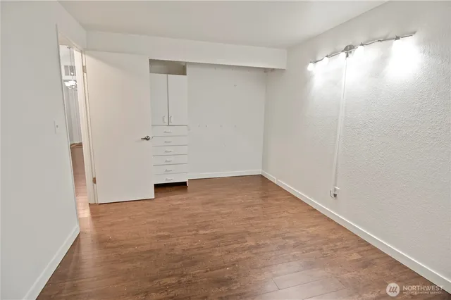 a view of an empty room with wooden floor and closet