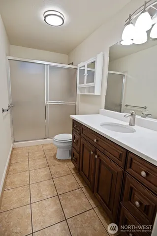 a spacious bathroom with a sink a toilet a mirror and shower