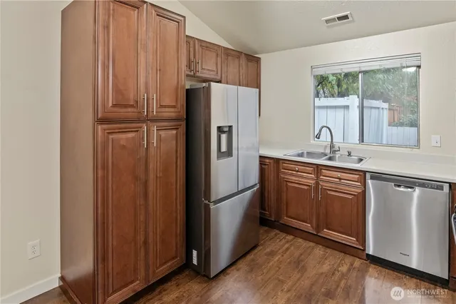 a kitchen with stainless steel appliances granite countertop a refrigerator a sink and dishwasher