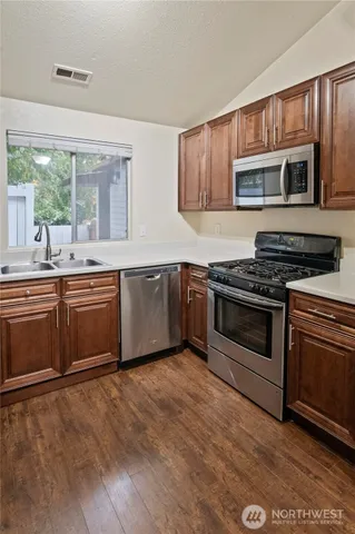 a kitchen with stainless steel appliances granite countertop a stove top oven microwave and sink