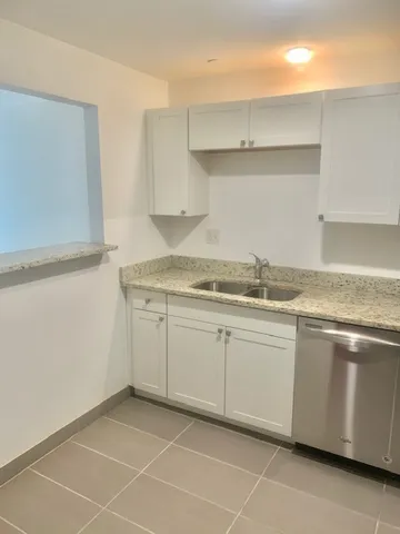 a white kitchen with granite countertop a sink