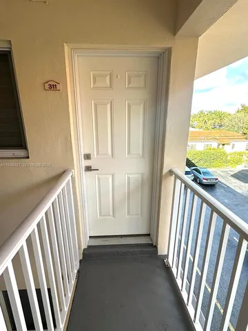 a view of a porch with wooden floor and door