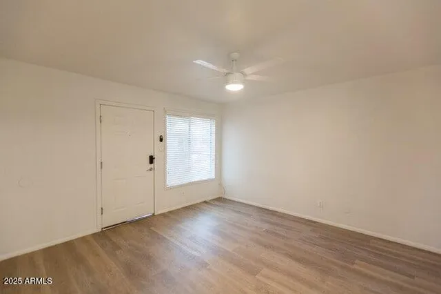 a view of an empty room with wooden floor and a window