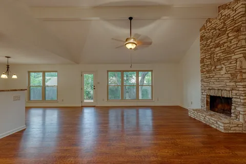 an empty room with wooden floor fireplace and windows