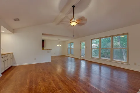 a view of an empty room with a window and wooden floor