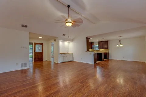 a view of an empty room with window and wooden floor