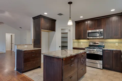 a kitchen with kitchen island granite countertop stainless steel appliances and wooden cabinets