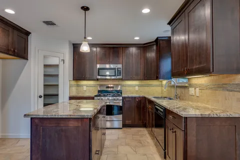 a kitchen with kitchen island granite countertop stainless steel appliances a sink stove and cabinets