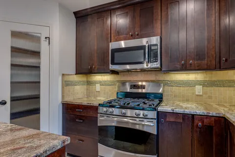a kitchen with granite countertop wooden cabinets and stainless steel appliances