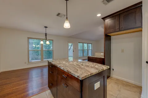 a kitchen with granite countertop kitchen island a stove and a wooden floor