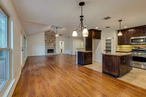 a open kitchen with stainless steel appliances granite countertop a sink a stove and a wooden floors