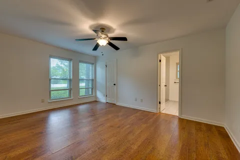 a view of an empty room with a window and wooden floor