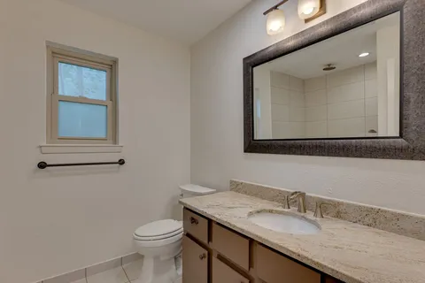 a bathroom with a granite countertop toilet sink and mirror