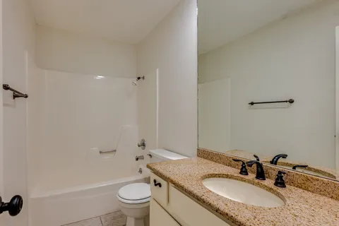 a bathroom with a granite countertop sink a toilet and a mirror