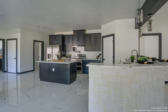 a large kitchen with kitchen island granite countertop a refrigerator a sink and dishwasher