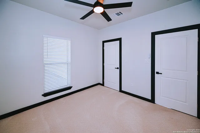 an empty room with closet and a ceiling fan