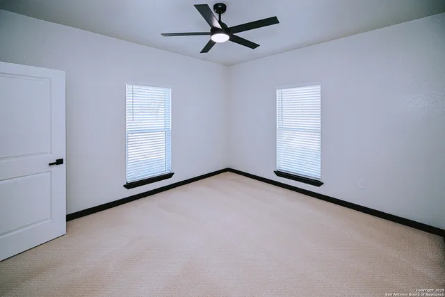 an empty room with windows and fan